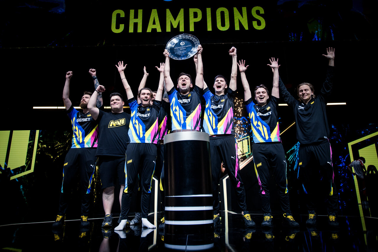The IEM Rio 2024 champions lifting the trophy under blue and yellow lights.
